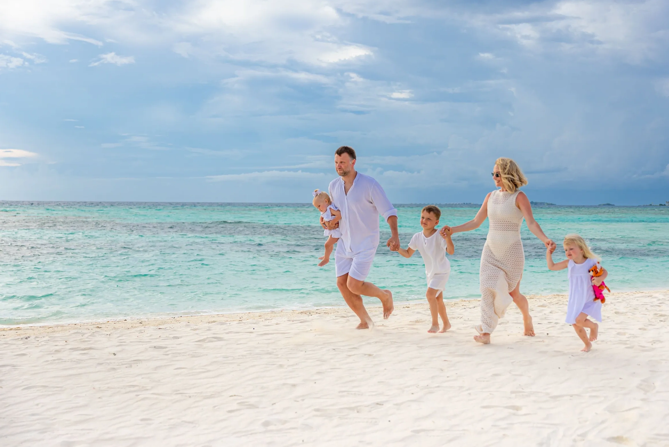A young family walking together along a white-sand Bali beach