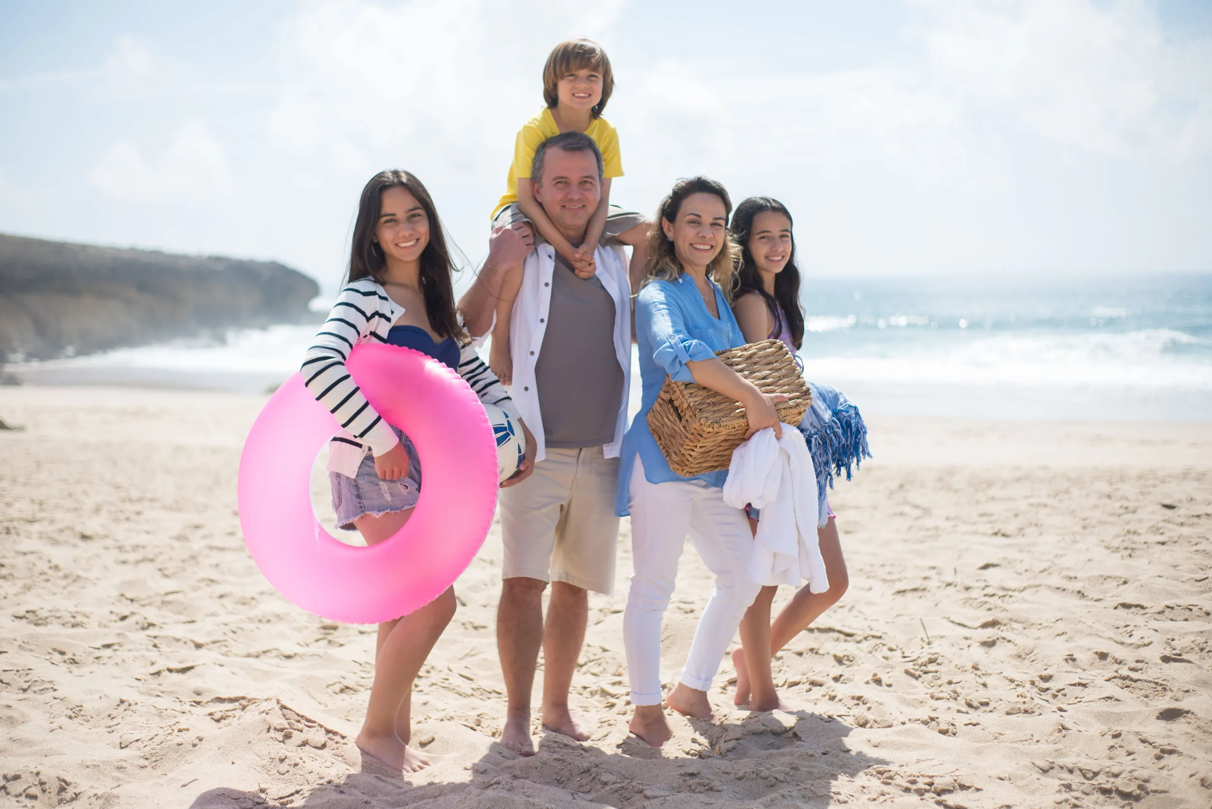A family at the beach in Bali with a pool ring, towels and holiday gear
