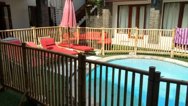 Bamboo pool safety fence enclosing a villa pool area with lounge chairs and tropical landscaping
